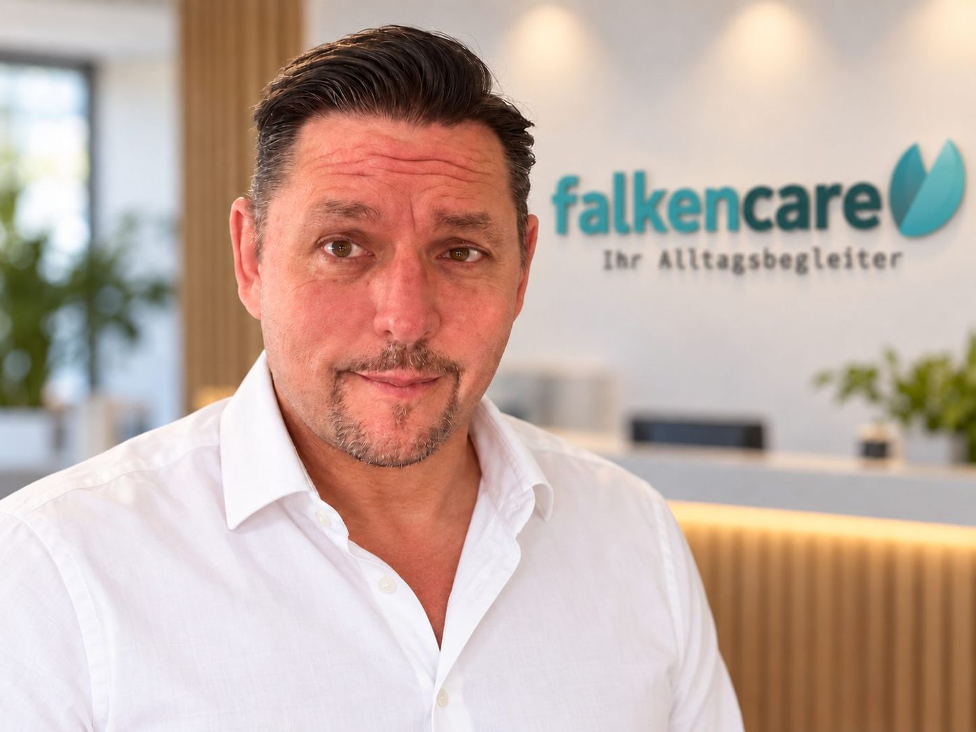Heiko Kukuk, Gründer von Falken Care, vor dem Firmenlogo im Büro
