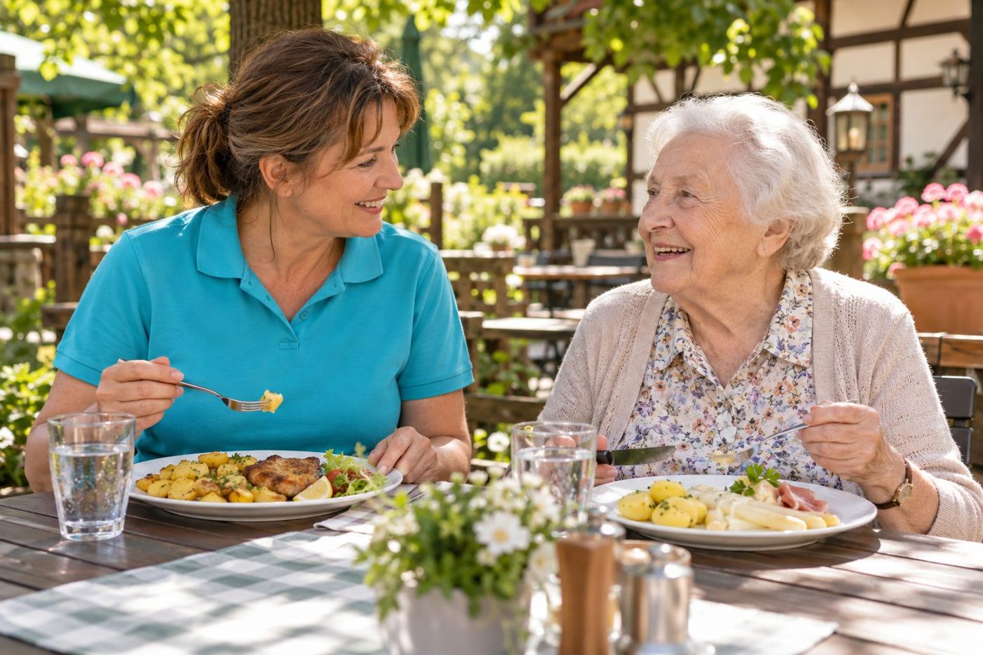 Mittagessen mit Begleitung: Alltagsbegleiterin und Seniorin essen gemeinsam im Biergarten eines Gasthauses